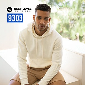 Model in an off-white Next Level Apparel 9303 Santa Barbara pullover hoodie sitting indoors; NL “9303” badge visible.