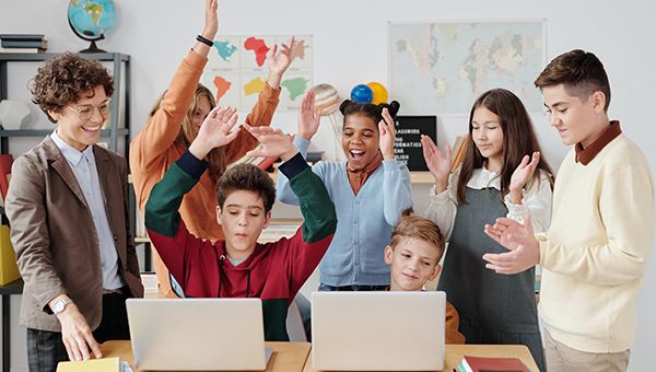 Students Teamwork in Classroom – Collaborative Learning with Laptops students collaborating around laptops in classroom teamwork learning environment